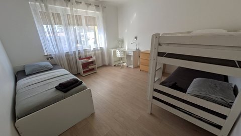 Chambre 2 de la maison : un lit simple et deux lits superposés, avec bureau et rangements