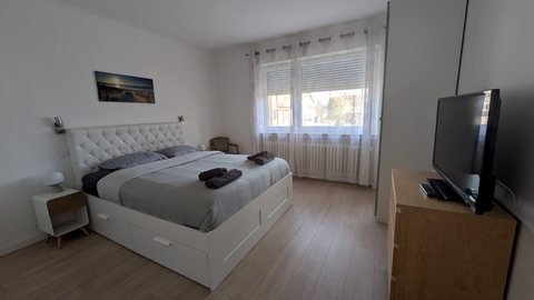 Chambre principale de la maison : lit double 160 cm, tête de lit capitonnée et téléviseur