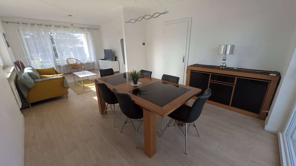 Séjour et salle à manger de la maison 3 chambres, avec baie vitrée sur le jardin